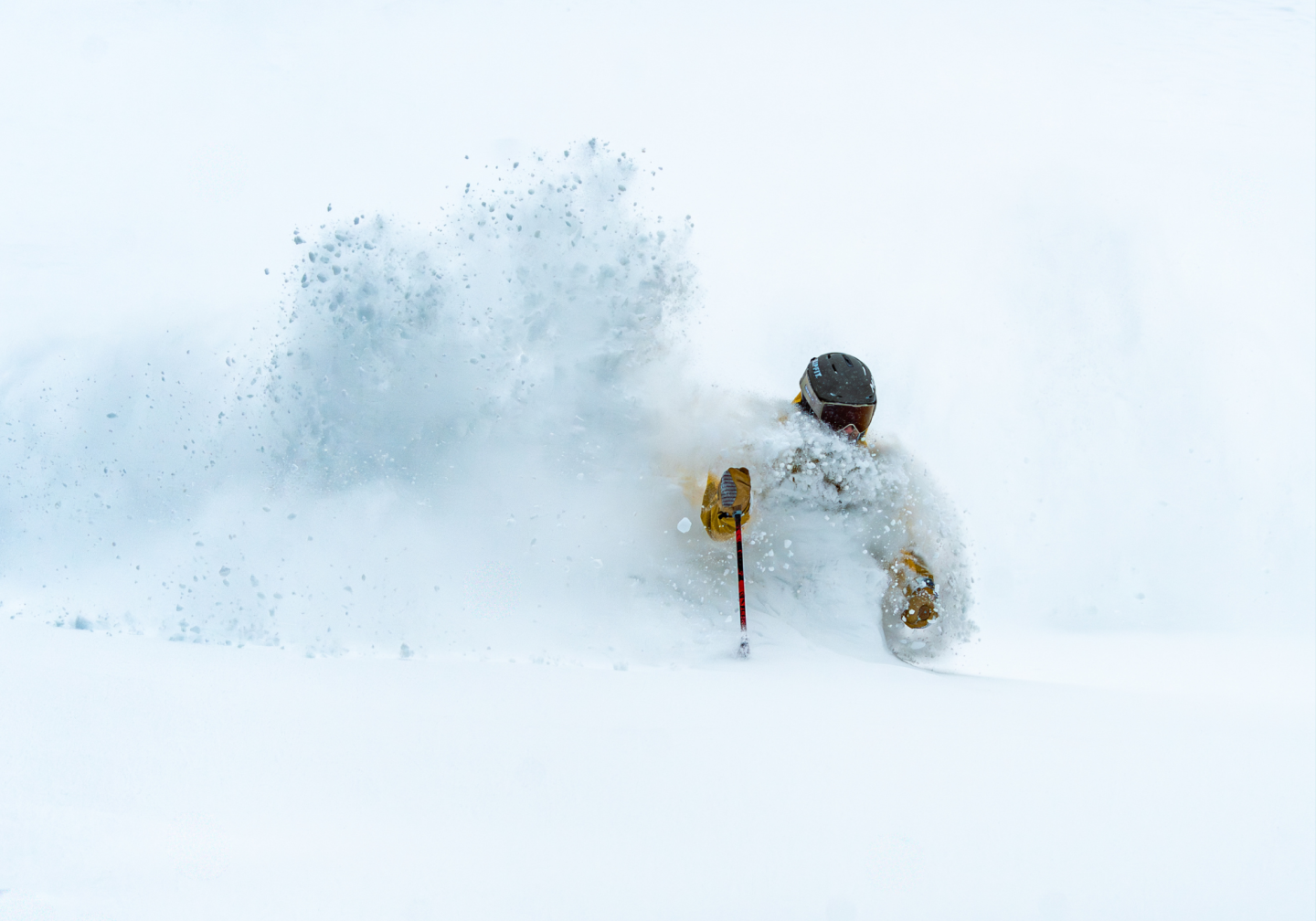 Person skiing through deep powder snow, partly obscured by spray.
