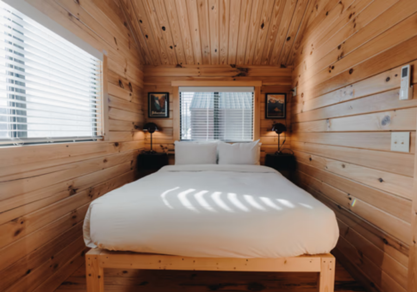 Cozy wood-paneled bedroom with a white bed and large windows.