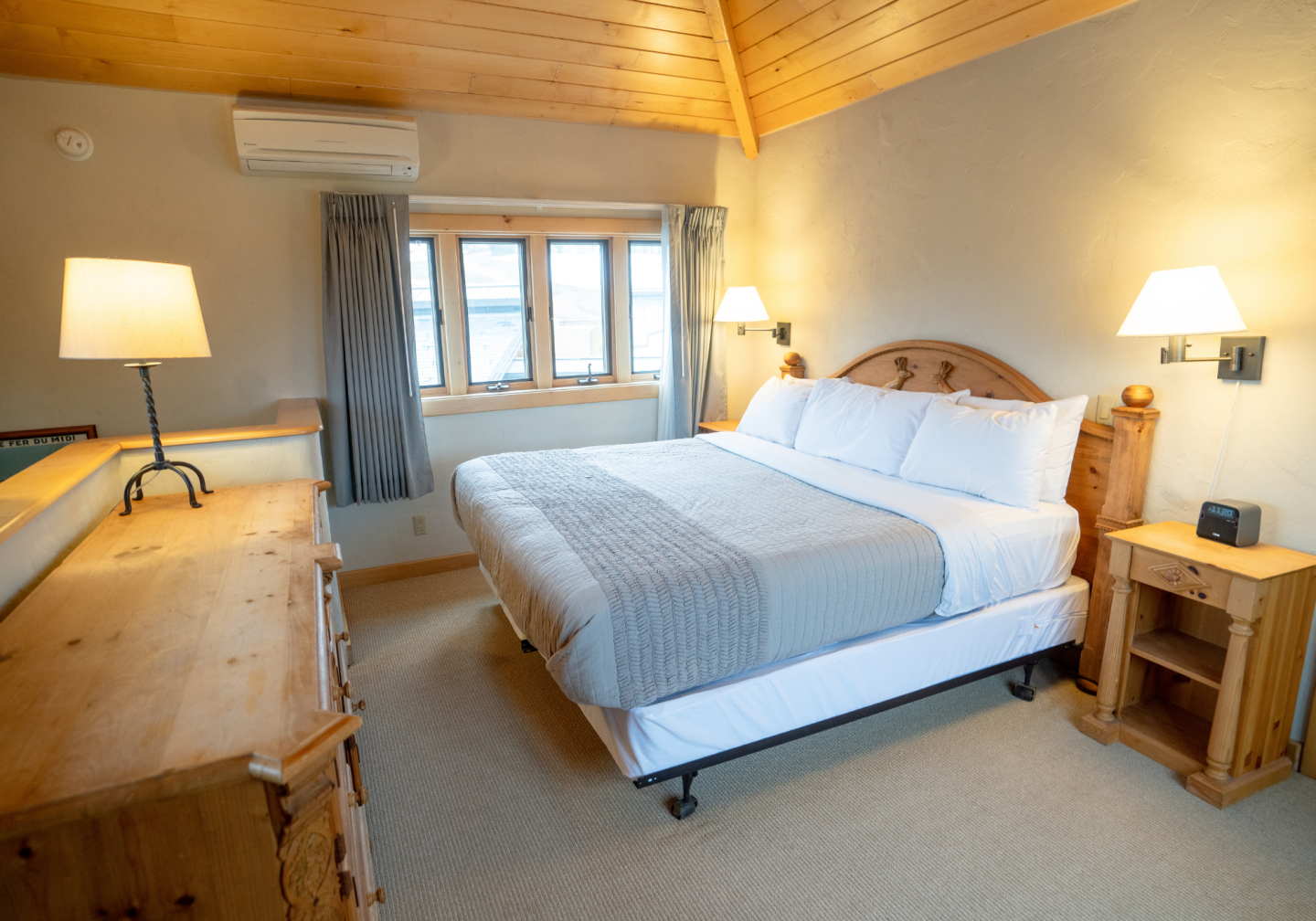 Cozy wood-paneled bedroom with twin beds, lamps, and a large dresser.