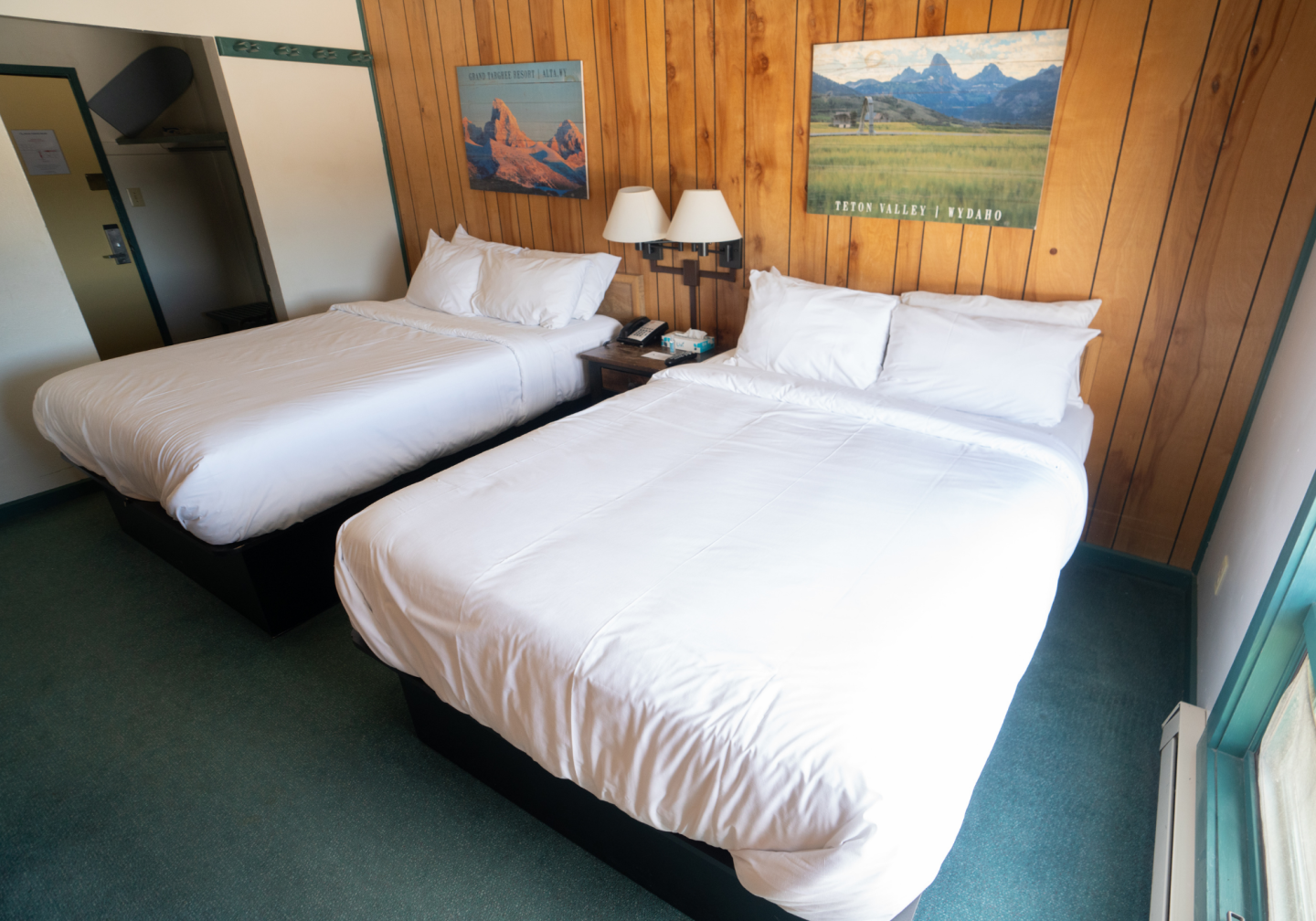 Cozy wood-paneled hotel room with two neatly made double beds.